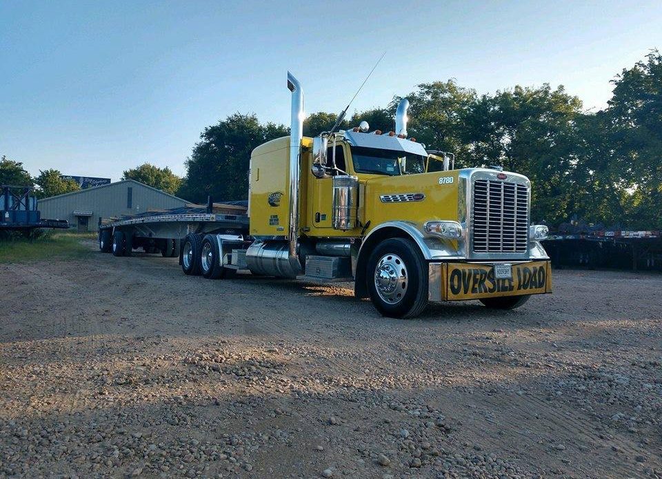 A Roane Transportation yellow semi truck with a flatbed trailer behind it.